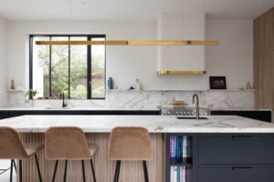 Bespoke navy and oak kitchen island with brass pendant light and marble countertop, handmade by Woodale Designs in Ireland.